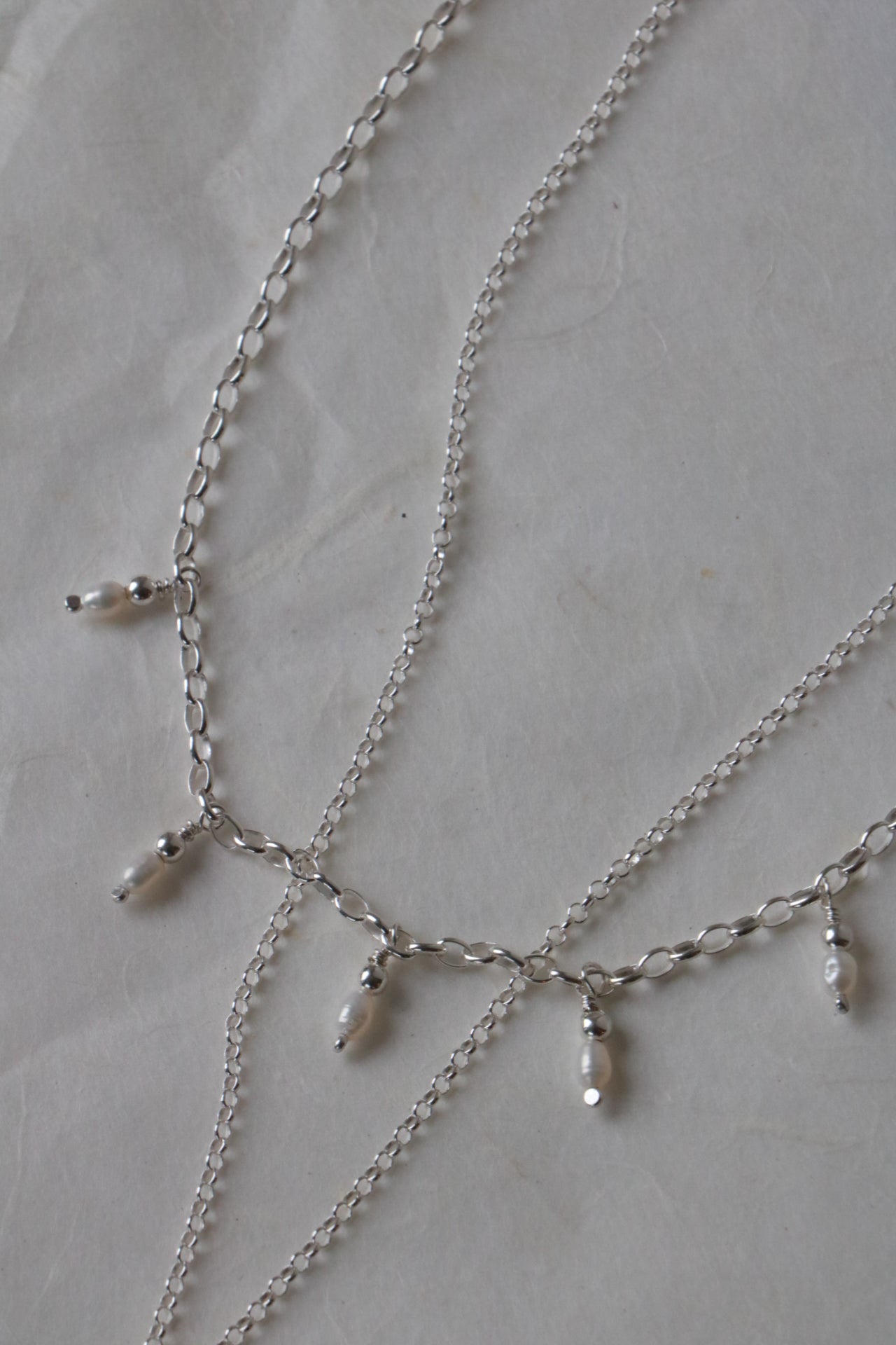 Silver chain necklace with small beads on a light gray surface
