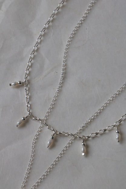 Silver chain necklace with small beads on a light gray surface